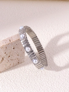 Dettaglio del bracciale elastico argento con perle d'acqua dolce su sfondo di pietra