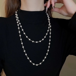Gros plan d'un collier de perles artificielles double couche sur un col roulé noir