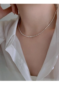 Close-up of minimalist silver collar necklace worn by model in a white shirt