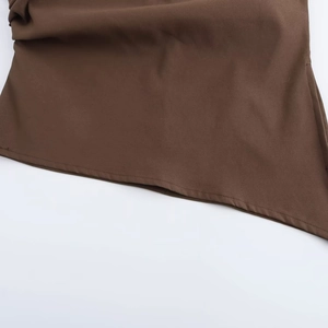 Close-up of brown sleeveless top featuring irregular hemline and precise stitching detail