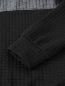 Detail of waffle knit fabric and ribbed cuffs on a grey and black patchwork hoodie