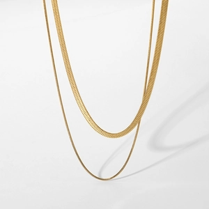 Detail of double-layered gold snake chain necklace with flat herringbone design on white background