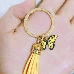 Detail of yellow butterfly keychain with a matching tassel held in a person's palm