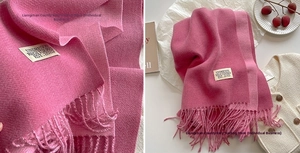 Close-up of vibrant pink cashmere-like scarf showing texture and elegant long tassels