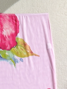 Detail of pink mesh fabric with large floral print and machine-stitched hem and wash tag