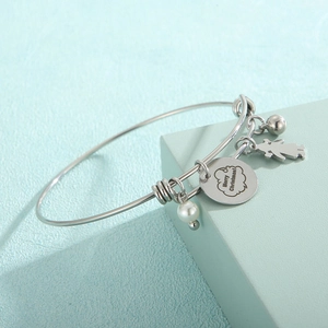 Détail du bracelet en acier argenté avec breloque fille, perle et gravure Joyeux Noël
