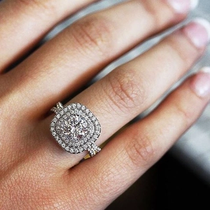 Macro shot of double halo round diamond ring with pavé stones on a white gold band