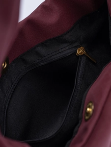 Detail shot of the burgundy suede shoulder bag's black interior lining and gold zipper