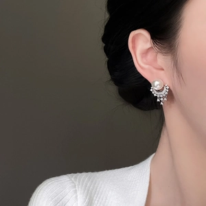 Close-up of elegant pearl drop earrings with sparkling diamond fringe on a female model