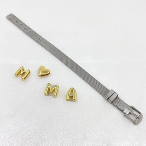 Close-up of Milanese mesh bracelet with gold-tone charms and heart buckle detail