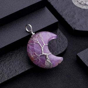 Macro shot of purple crystal moon pendant with silver wire tree of life wrapping