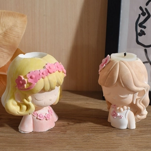 Detail view of two cute girl-shaped candle holders with a tea light candle insert