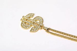 Macro shot of gold dollar sign pendant with sparkling diamonds and curb chain