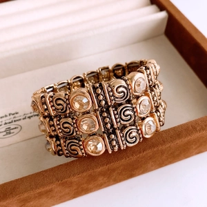 Detailed close-up of vintage gold stretch bracelet with crystals and spiral patterns
