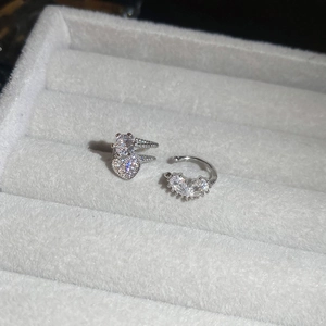 Macro shot of silver zircon heart ear cuff and stud earring in a grey velvet jewelry box