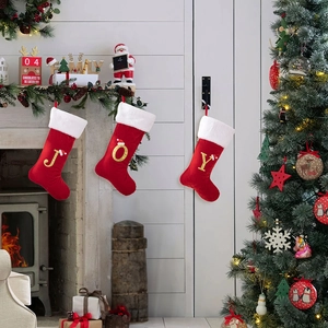 Dettaglio di tre calze di Natale in velluto rosso con lettere JOY ricamate in oro