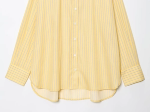 Vista dettagliata di una camicia casual gialla a righe con maniche lunghe e orlo curvo