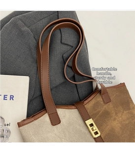 Detail of canvas tote bag featuring brown faux leather handle and gold metal lock buckle