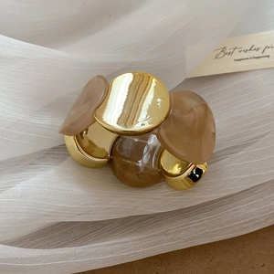 Détail d'un bracelet en acrylique ambré et métal doré sur fond de tulle blanc élégant