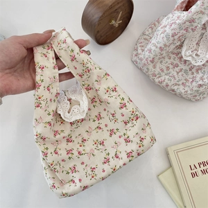 Detail of floral canvas tote with white lace trim and vintage clock on white surface