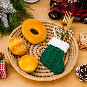Close-up of green knitted Christmas stocking pocket with golden cutlery on wooden table