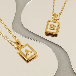 Minimalistische Goldketten mit quadratischen Buchstaben-Anhängern A und B auf weißem Inlay