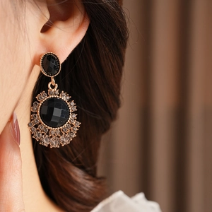Gros plan de boucles d'oreilles fleurs vintage avec pierres noires et cristaux