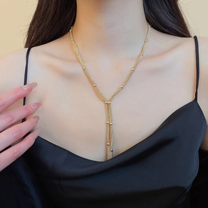 Detailed close-up of a golden multi-layered fringe Y-necklace worn by a model