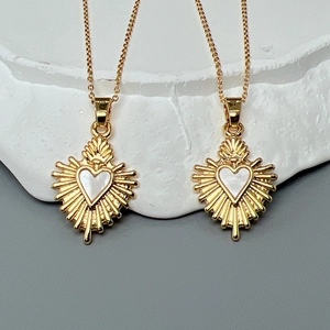 Elegant gold heart pendant necklace with sunburst shell inlay on minimalist stone surface