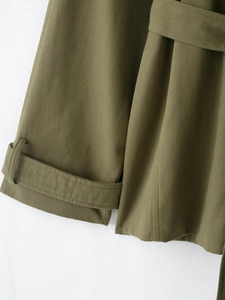 Detail of adjustable belted cuffs and rugged canvas texture on army green trench coat