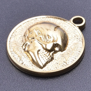 Macro view of gold skull pendant with relief carving on textured dark background