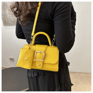 Detailed view of yellow faux leather handbag with gold buckle and mini coin purse attachment