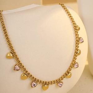 Detail of gold heart charms and pink crystal pendants on a stainless steel fringe necklace