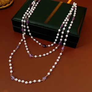 Detailed macro view of layered necklace featuring white pearls and purple amethyst stones