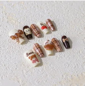 Detail of 3D bear nail art stickers with brown plaid pattern and cherry charms