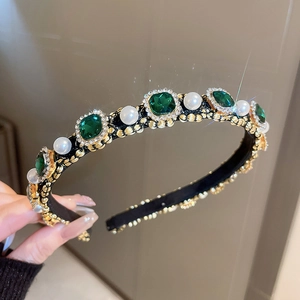 Close-up of vintage headband with emerald crystals, white pearls and gold metal base