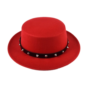 Macro detail of red wool flat top hat featuring a black leather belt with silver studs