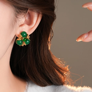 Vue détaillée des boucles d'oreilles vintage avec perles vertes et socle fleuri doré