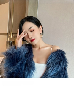 Detail shot of elegant gold pearl drop earrings paired with a plush blue faux fur coat