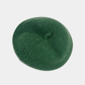 Dettaglio di un berretto in maglia verde scuro con trama spessa e piccolo stelo in cima