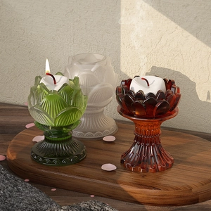 Three-color lotus flower glass candle holders on a wooden tray with elegant side lighting