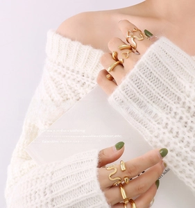 Detail of gold U-shaped wavy rings on model's fingers showing minimalist geometry