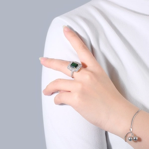 Detail of s925 silver ring with emerald cut green stone and silver bell bracelet