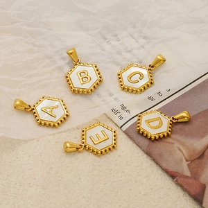 Detailed view of hexagonal 18K gold plated pendants with mother of pearl and A-E initials