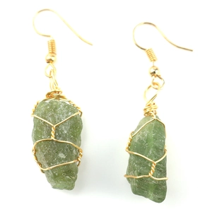 Macro detail of handmade gold wire-wrapped raw green natural crystal stone earrings
