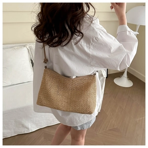 Detail of woven straw tote bag with fine texture and minimalist strap on model