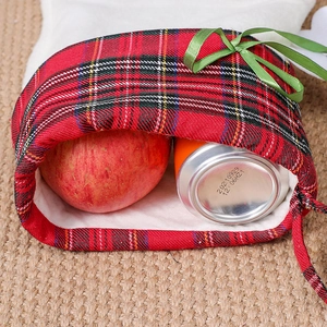 Détail du sac cadeau de Noël à carreaux rouges avec nœud montrant la capacité de stockage