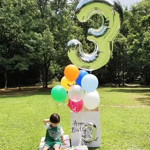 Silver foil number 3 balloon with colorful latex balloons and birthday gift box on grass