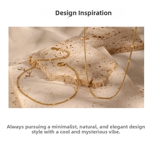 Close-up of a minimalist gold chain necklace with shiny sequins on a beige stone surface