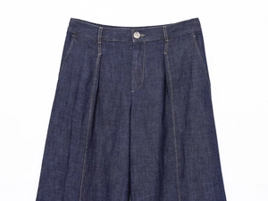 Dettaglio di pantaloni in denim blu scuro con pieghe e chiusura con bottone metallico
